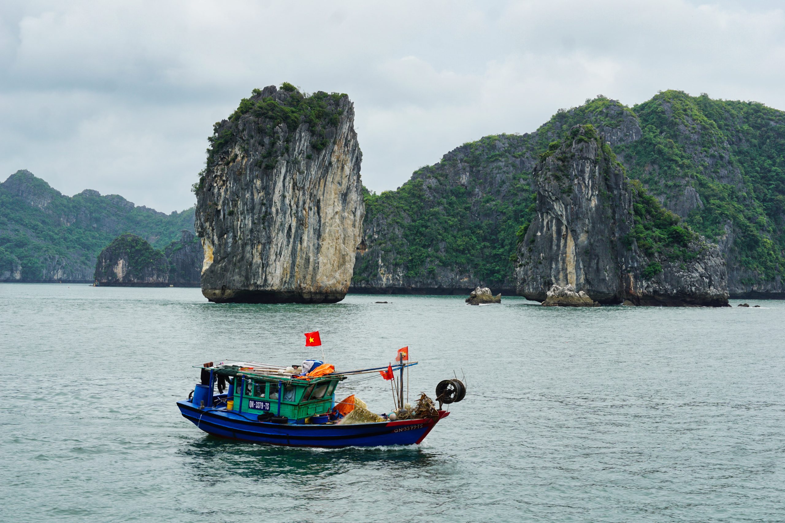 Ein kleines Fischerboot bahnt sich seinen Weg durch die Halong Bucht